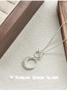 Macro view of frosted S925 sterling silver crescent moon pendant with an OT toggle clasp