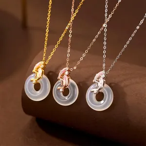 Macro view of three jade-like circle pendants with elegant gold dolphin accents