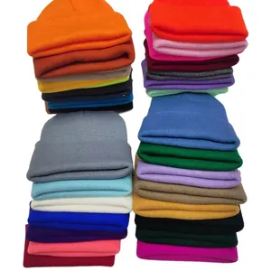 Close-up detail of multi-colored solid knit beanies stacked on a clean white background
