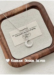 Close-up of s925 sterling silver moon pendant necklace with OT buckle on a wooden tray