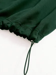 Close-up detail of the adjustable drawstring toggle on a dark green sports jacket hem.