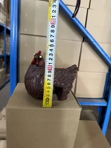 Detailed view of a brown hen garden ornament being measured for scale with a yellow tape.
