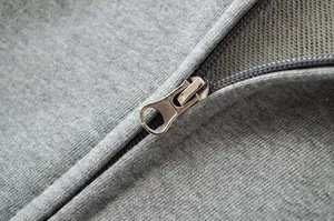 Detailed close-up showing the metal zipper and fabric texture of a gray hooded sweatshirt