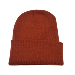 Close-up of burnt orange knitted beanie with ribbed texture and folded cuff detail.