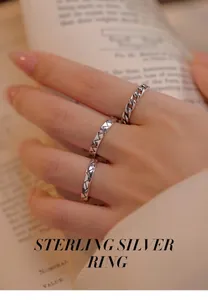 Close-up of three S925 sterling silver rings worn on a hand holding a book