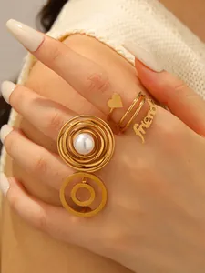 Detailed close-up of a gold-plated pearl spiral ring and cursive friend letter ring