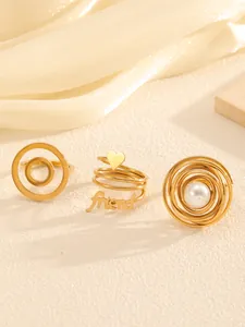 Close-up of three gold-plated titanium steel rings with pearl and heart detail