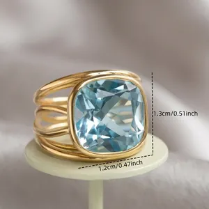 Elegant gold-tone cocktail ring featuring a square blue crystal and a unique streamlined band design