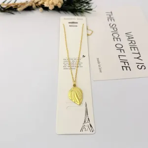 Détail d'un collier avec pendentif feuille dorée sur une carte cadeau.