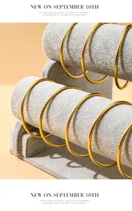 Detailed macro view of a grey velvet 3-tier jewelry stand holding golden bangles