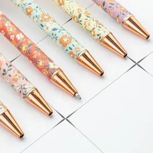 Elegant set of floral ballpoint pens with rose gold trim on a minimalist grid background