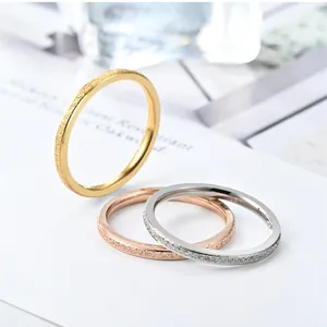 Close-up of frosted minimalist stainless steel rings in gold, silver, and rose gold.