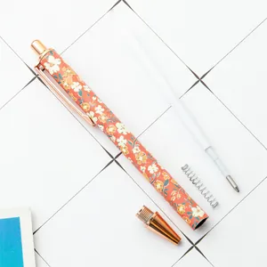 Floral retractable ballpoint pen with rose gold accents and disassembled internal parts