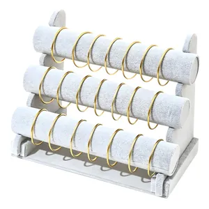 Three-tier grey velvet jewelry display stand for bracelets and watches on white background
