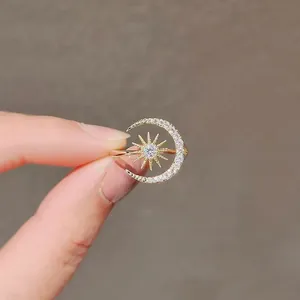Close-up of a gold-plated crescent moon and sunburst ring with pave rhinestones