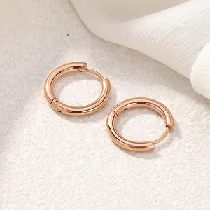 Close-up of minimalist rose gold titanium steel round hoop earrings on white fabric
