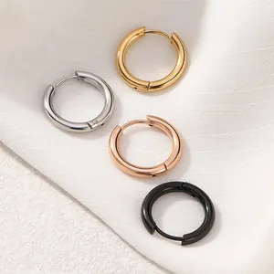 Detailed macro view showing four colors of stainless steel hoop earrings on white fabric.