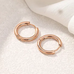 Macro detail of minimalist rose gold titanium steel round hoop earrings on white background