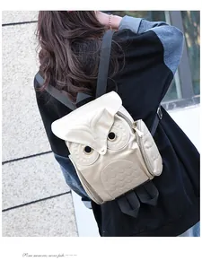 Back view of a woman carrying a 3D owl-shaped gold backpack in a casual street setting.