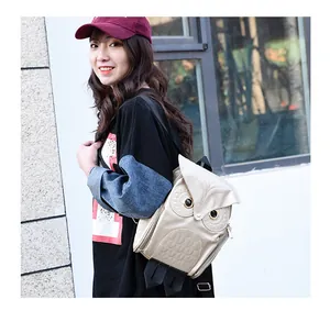Stylish golden owl-shaped backpack worn by a model in an urban outdoor street setting