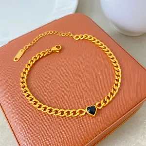 Detail view of a gold plated titanium steel heart necklace with a black stone on a box