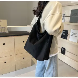 Modell trägt eine große schwarze matte Einkaufstasche in minimalistischer Umgebung