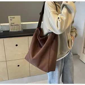Große braune Shopper-Tasche aus Wildleder-Imitat, getragen von einem Model in einem Zimmer