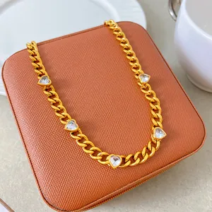 Detail of a gold-plated stainless steel cuban chain necklace with heart zircon charms.
