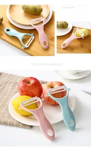 Close-up of ceramic vegetable peelers in pink and blue on a wooden board