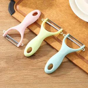 Set of three colorful Y-shaped vegetable and fruit peelers presented on a wooden board