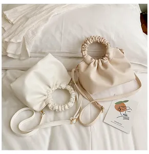Deux sacs à main minimalistes en cuir PU plissé avec poignées froncées sur lit blanc
