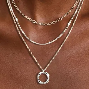 Detailed view of a silver three-layered necklace featuring a twisted circle pendant.