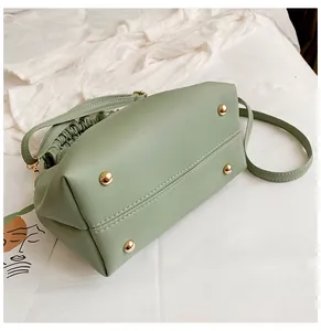 Détail du fond du sac en similicuir vert clair montrant les pieds de protection dorés.