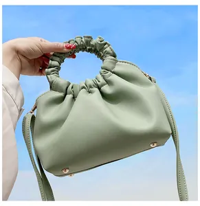 Gros plan d'un sac à main plissé vert menthe en cuir PU avec poignée froncée sur ciel bleu