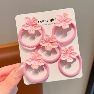 Set of five pink cherry blossom elastic hair ties for girls shown on a white display card