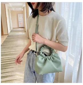 Détail rapproché d'un sac à main en cuir PU plissé vert menthe tenu par un mannequin asiatique.