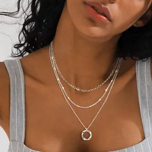 Close-up view of a three-layer silver necklace featuring a twisted circle pendant detail
