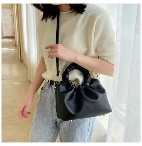 Gros plan d'un sac à main noir en cuir PU plissé porté par un mannequin.