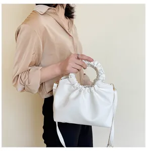 Détails d'un sac à main blanc plissé avec une poignée circulaire et dorures en or