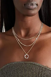 Detail of triple-layer silver necklace with twisted chain and circle pendant on model