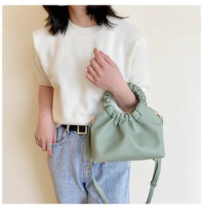 Modèle tenant un sac à main en PU froncé vert sauge avec texture douce