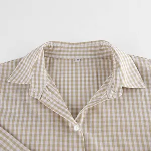 Detailaufnahme eines beigen Gingham-Pyjamahemdkragens mit M-Etikett und weißem Knopf.