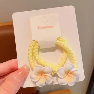 Sweet pair of yellow braided elastic hair ties featuring white plumeria flower accents
