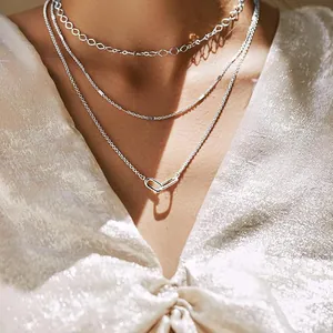 Detailed close-up of a triple-layered silver necklace with distinct chain styles and pendant.