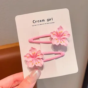 Close-up of pink cherry blossom hair clips on a white display card