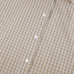 Nahaufnahme von beigem Gingham-Baumwoll-Pyjamastoff mit eleganten weißen Knöpfen