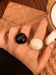 Close-up of black and white circular enamel rings on hand in warm autumn tones