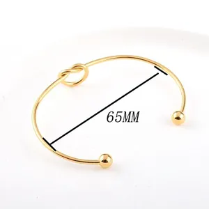 Close-up detail of minimalist gold knotted stainless steel cuff bracelet with 65mm diameter