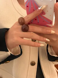 Detail view of stylish retro chocolate and caramel colored round enamel rings on a hand