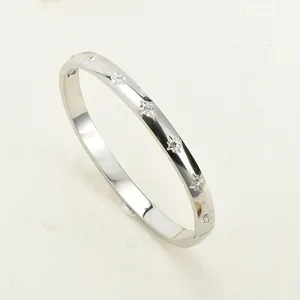Polished silver stainless steel bangle bracelet featuring engraved star patterns with rhinestones